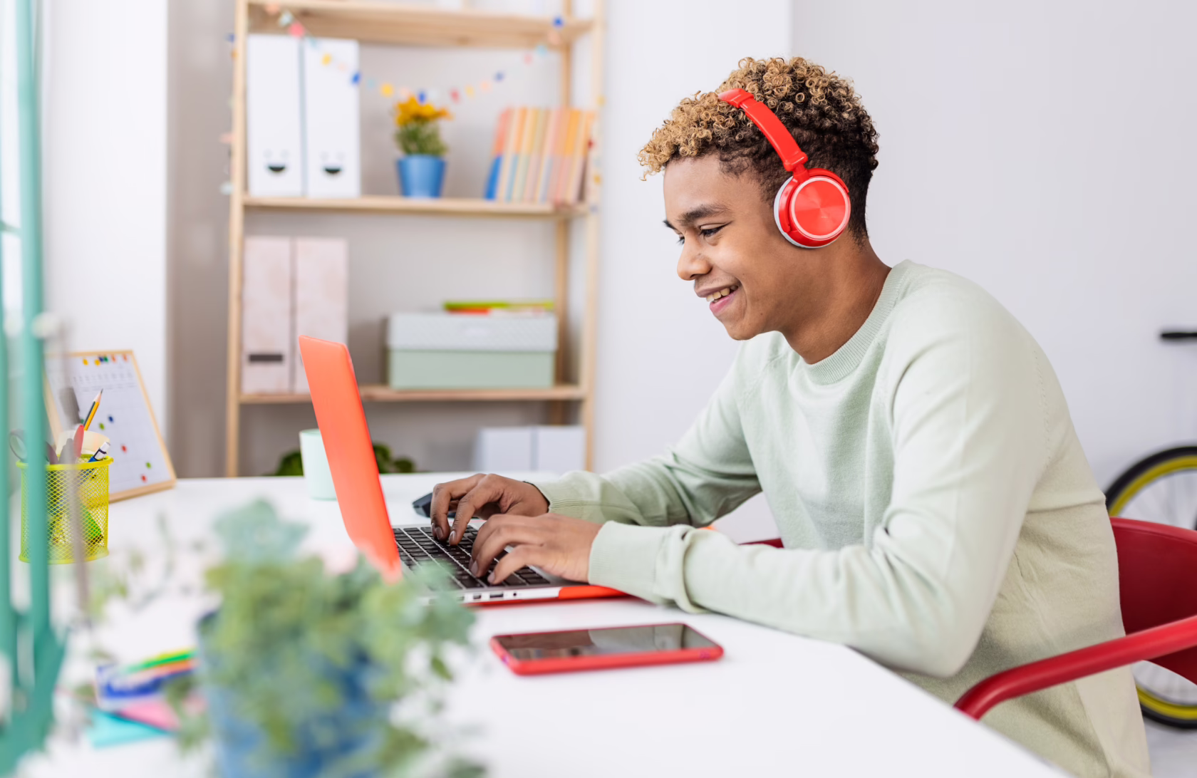 Happy young teenage boy studying online at home