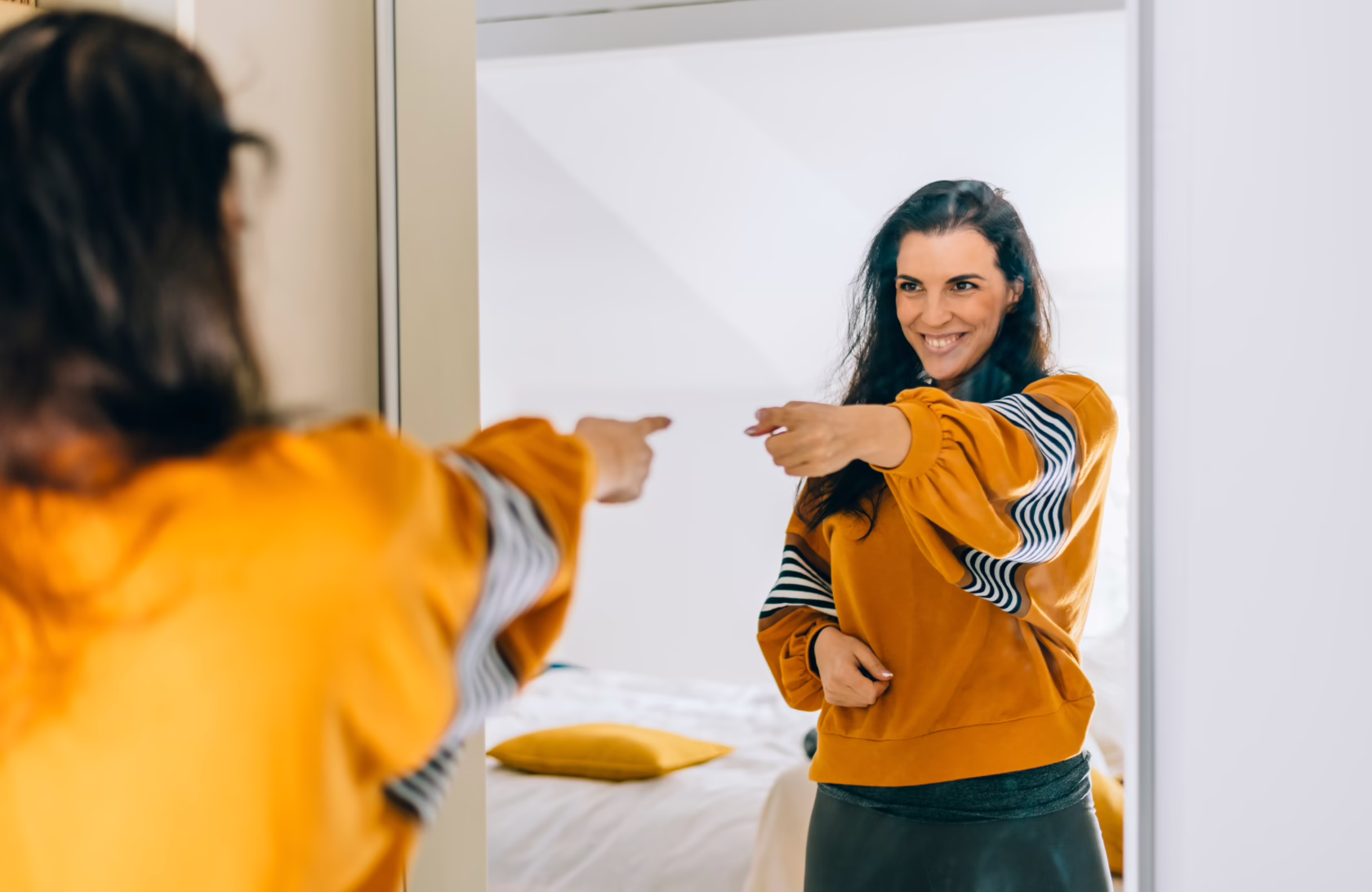 Self confident single woman pointing finger at reflection in mirror dancing and felling good. Independent person with high self esteem talk positive I can do it motivation.