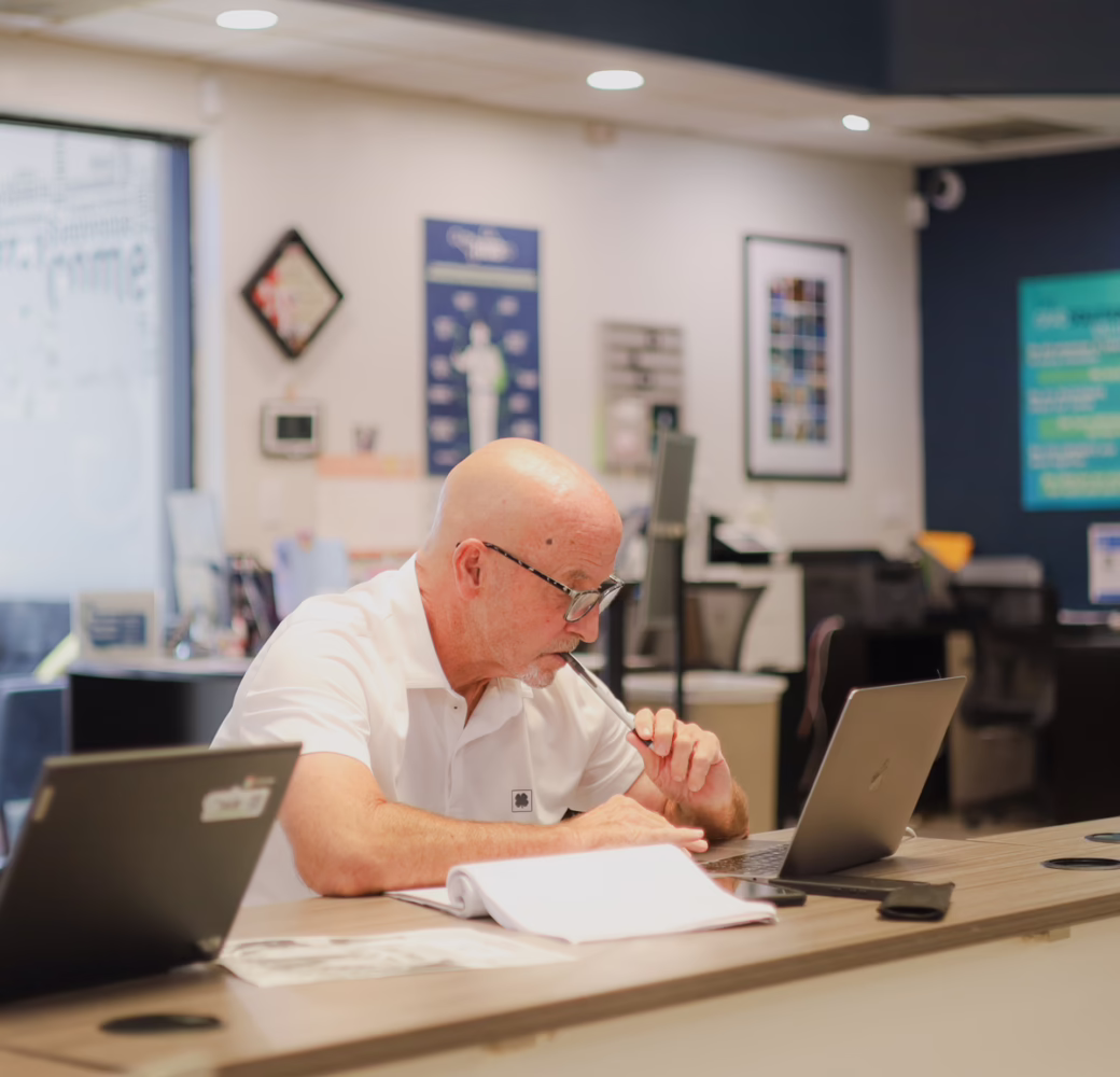 Adult learner works on a laptop at a table in a HUB student resource center, reviewing notes and course materials.