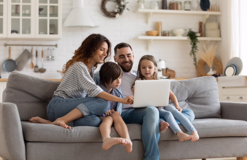 Family gathered around a laptop at home, illustrating how education can create new opportunities and a brighter future for the whole family.