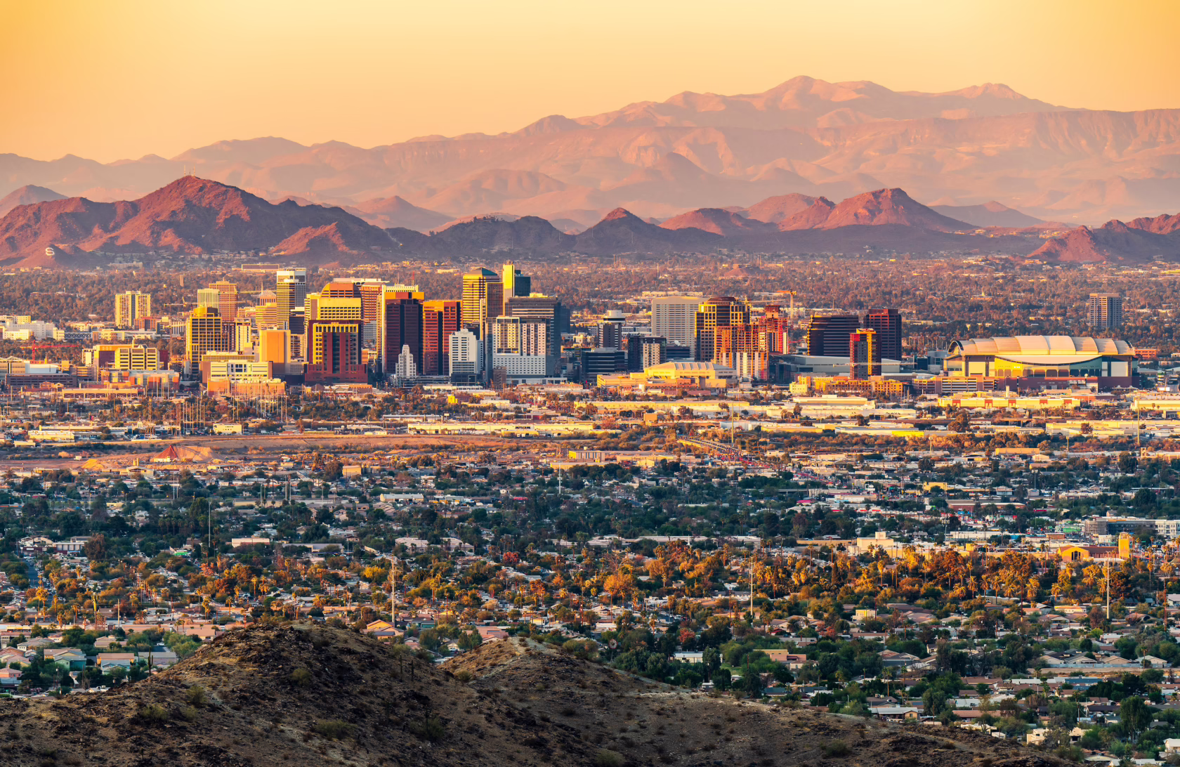 Phoenix skyline at sunset with desert mountains in the background.