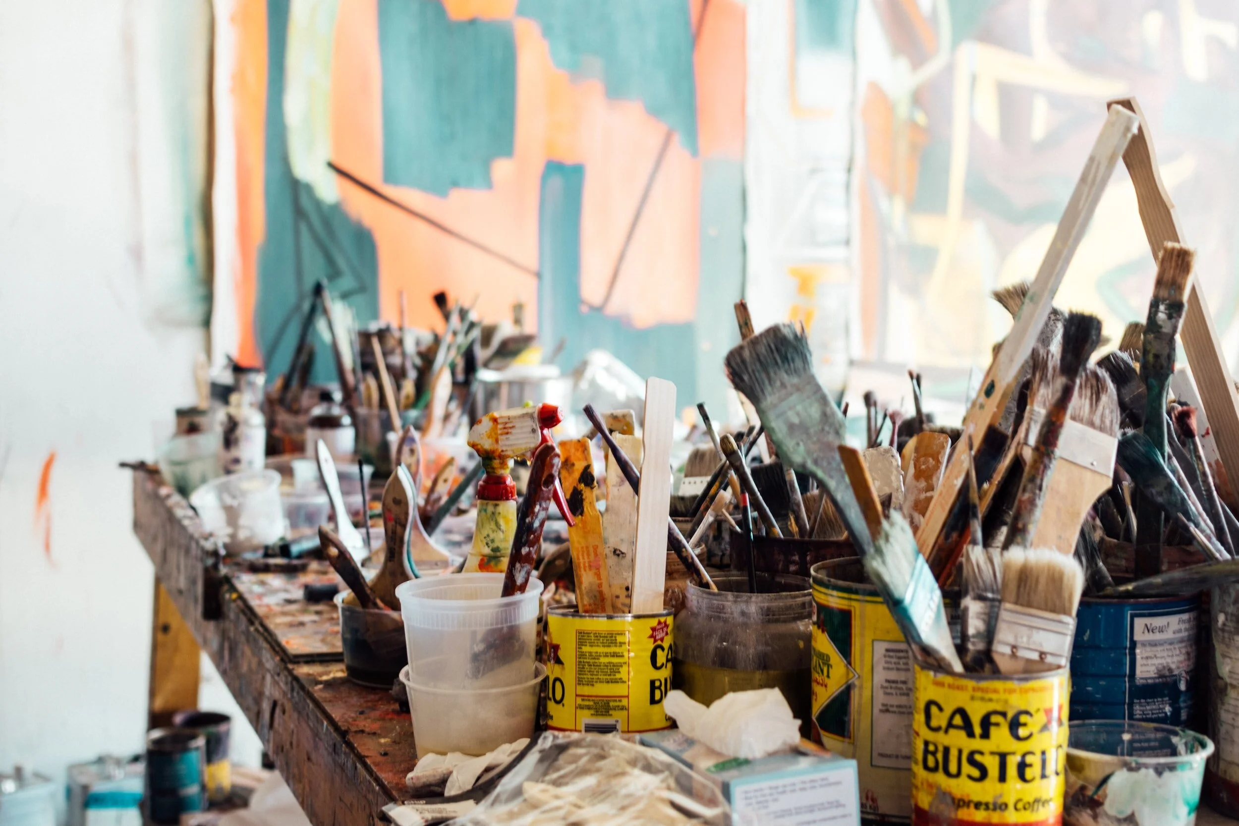 Paintbrushes, palette knives, and art supplies arranged on a worktable in a painter's studio.